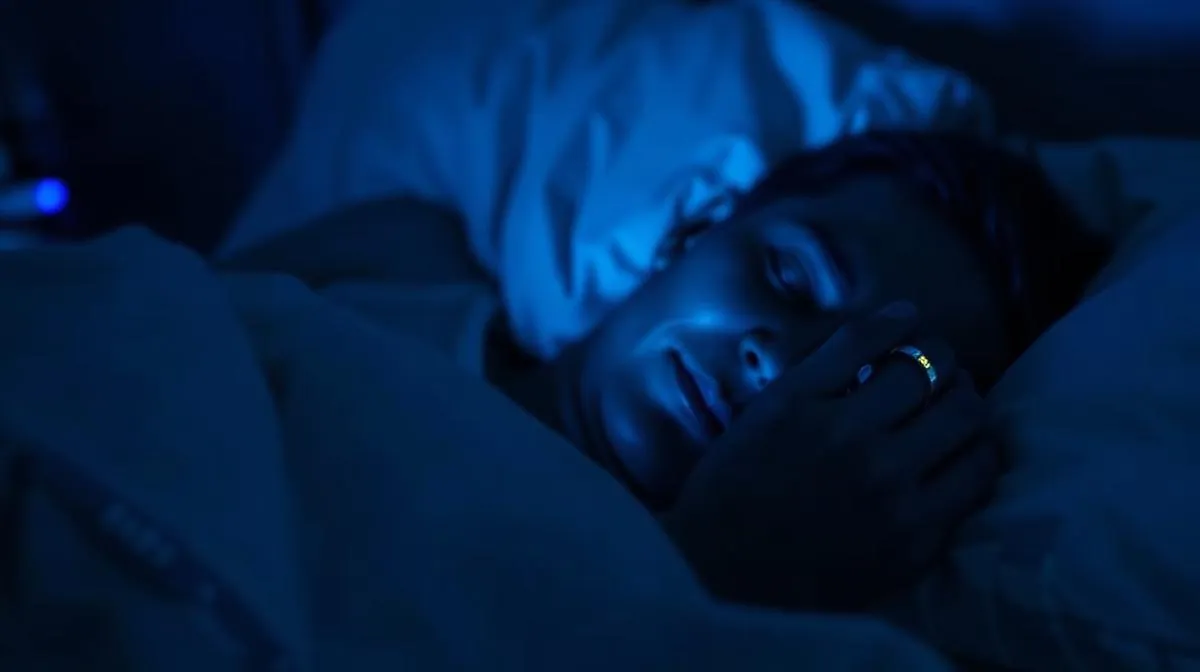 Person sleeping peacefully with a smart ring glowing subtly on their finger, representing overnight sleep tracking technology